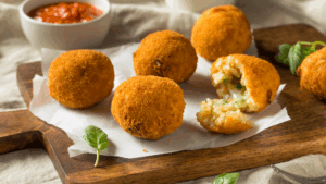Uma explosão de sabor e textura: crocantes por fora, cremosos por dentro. Esses arancini são recheados com a combinação perfeita de azeitonas verdes e pimentões picantes, envoltos em arroz Arborio temperado com alho e levedura nutricional. Tudo isso empanado em farinha panko e assado na air fryer até dourar. Uma verdadeira delícia italiana sem culpa!