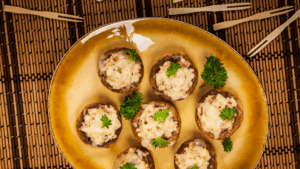Uma explosão de sabor e textura: cogumelos macios recheados com uma mistura cremosa de feijões brancos, erva-doce grelhada e cebola-roxa, temperados com cominho, páprica defumada e coentro moído. Uma entrada sofisticada e saudável que vai impressionar seus convidados.