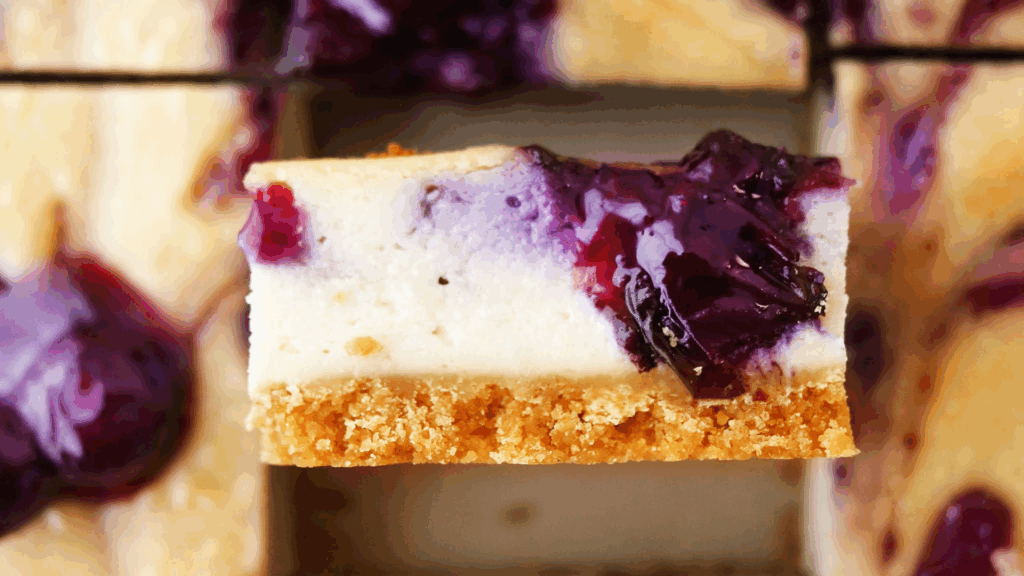 Barras Plant-Based de Cheesecake de Mirtilo com Creme de Batata-Doce e Limão 4 Uma sobremesa saudável, sem glúten e 100% plant-based, perfeita para impressionar em ocasiões especiais ou para um mimo no dia a dia. A base é adoçada naturalmente com tâmaras e enriquecida com manteiga de girassol, enquanto o recheio cremoso combina castanhas de caju e batata-doce branca, finalizado com uma cobertura vibrante de mirtilos frescos. Uma explosão de sabor e textura que agrada a todos!